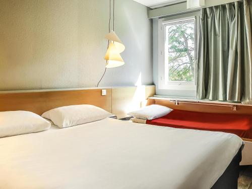 two beds in a hotel room with a window at ibis Salon de Provence in Salon-de-Provence