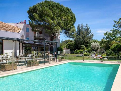 a swimming pool in front of a house at ibis Salon de Provence in Salon-de-Provence