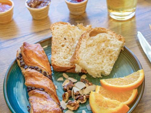 a plate of food with a piece of bread and orange slices at ibis Salon de Provence in Salon-de-Provence
