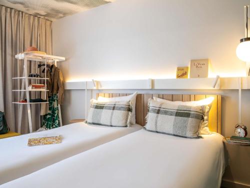 a bedroom with a large white bed with two pillows at ibis Maine Montparnasse in Paris