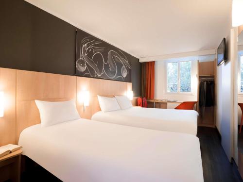 two beds in a hotel room with white sheets at ibis Maine Montparnasse in Paris
