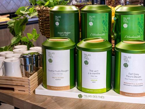 a group of green cans sitting on a shelf at ibis Maine Montparnasse in Paris