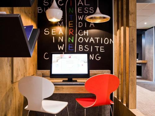 a desk with a computer and two red chairs at ibis Maine Montparnasse in Paris