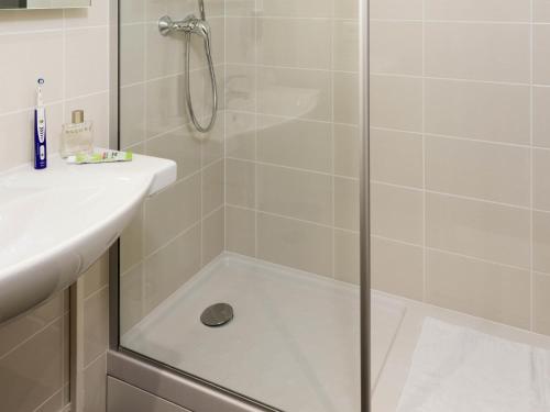 a shower with a glass door next to a sink at ibis Styles Paris Roissy-CDG in Roissy-en-France