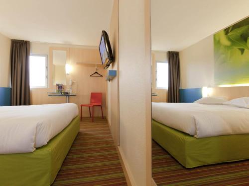 a hotel room with two beds and a tv at ibis Styles Paris Roissy-CDG in Roissy-en-France