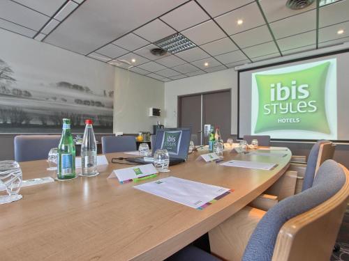 a conference room with a long table with bottles and chairs at ibis Styles Paris Roissy-CDG in Roissy-en-France