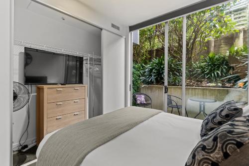 Un dormitorio con una cama y una ventana grande. en Victoria Park Haven w carpark, spa, pool and gym, en Auckland