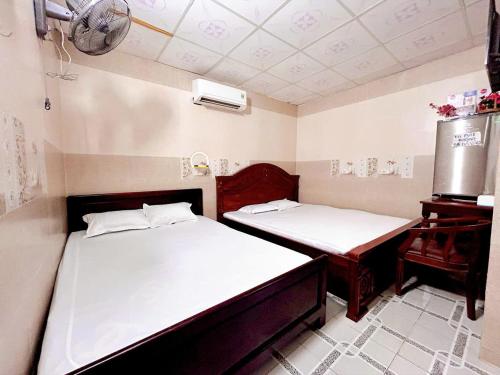 a room with two beds and a desk in it at Nhà Nghỉ Xuân Lan in Can Tho