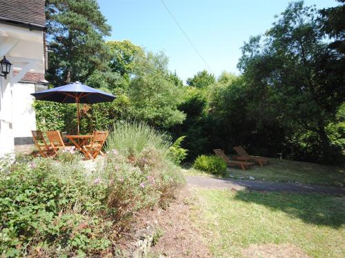 a table and chairs with an umbrella in a garden at 4 Bed in Studland DC046 in Studland