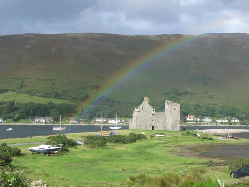 a rainbow over an old castle in front of a mountain at 2 Bed in Lochranza 77882 in Lochranza