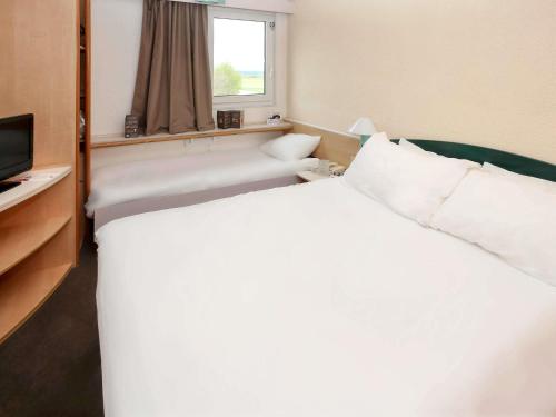 Una cama o camas en una habitación de ibis Auxerre Sud