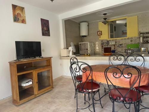 a kitchen with a table with chairs and a television at Auberge Villa des Jasmins in Aghroude