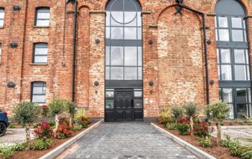 a brick building with a black door at Stay at 52 The Maltings, Burton on Trent - Modern One Bedroom Apartment in Burton upon Trent