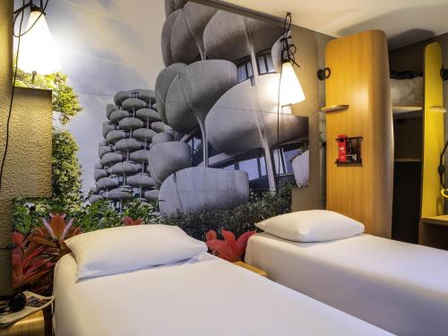 two beds in a room with a painting on the wall at ibis Paris Creteil in Créteil
