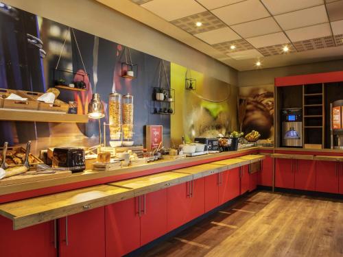 a restaurant kitchen with red cabinets and a counter at ibis Paris Creteil in Créteil