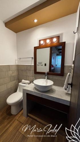 a bathroom with a sink and a toilet and a mirror at Hotel María Isabel Ataco in Concepción de Ataco