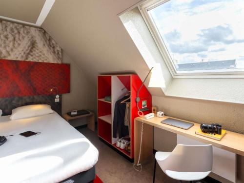 a bedroom with a bed and a desk and a window at ibis Epernay Centre Ville in Épernay