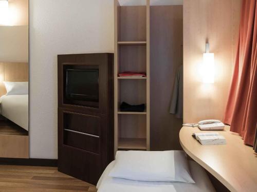 a room with a bed and a tv and a desk at ibis Angers Centre Chateau in Angers