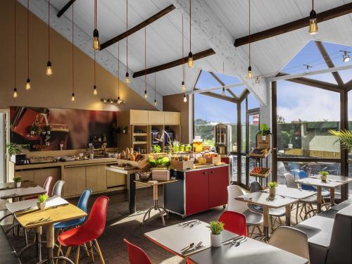een restaurant met tafels, stoelen en ramen bij ibis Saint-Nazaire - Trignac in Trignac