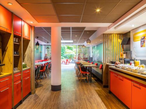 um restaurante com armários laranja, mesas e cadeiras em ibis Paris Gare du Nord La Fayette em Paris