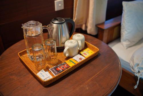 a wooden table with a tray with a tea pot and a glass pitcher at Belongas Bay Lodge LOMBOK in Blongas