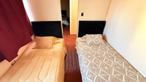 a small room with two beds in a room at CLAUSSMARY Hotel in Rancagua