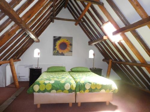a bedroom with a bed and a sunflower painting on the wall at Logementen Jannum in Birdaard