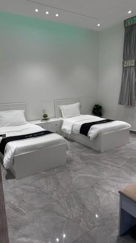 two beds in a room with white walls and marble floors at Liyali Chalet in Taif
