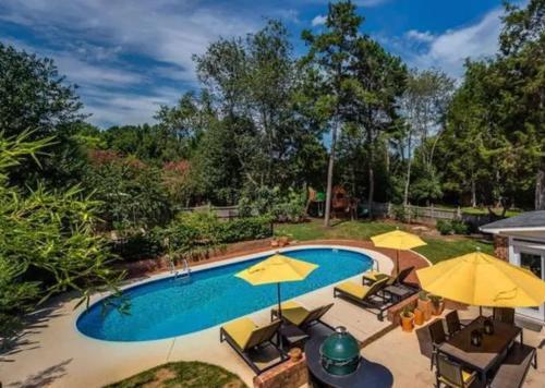 a swimming pool with chairs and umbrellas at Cozy Home with POOL plus CHEFS kitchen in Prime Area in Charlotte