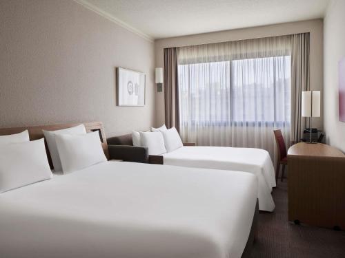 a hotel room with two beds and a window at Novotel Athens in Athens