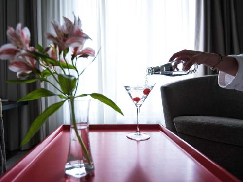 a woman pouring a glass of wine on a table with flowers at Novotel Athens in Athens