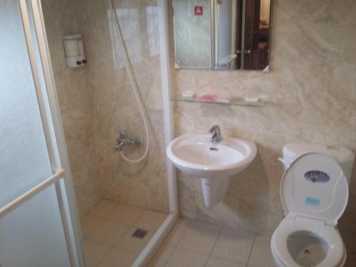 y baño con lavabo, aseo y ducha. en KD Hotel en Douliu