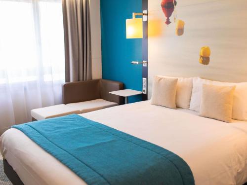 a hotel room with a bed and a chair at Mercure Lorient Centre in Lorient