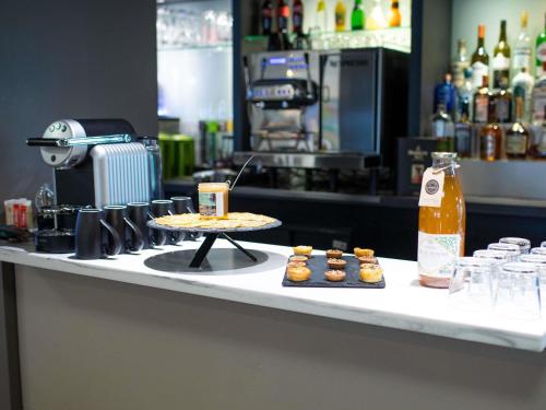 a counter with a table with a pizza and cupcakes at Mercure Lorient Centre in Lorient