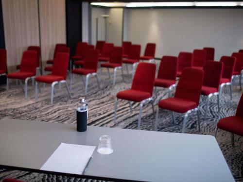 a conference room with red chairs and a bottle of soda at Mercure Lorient Centre in Lorient