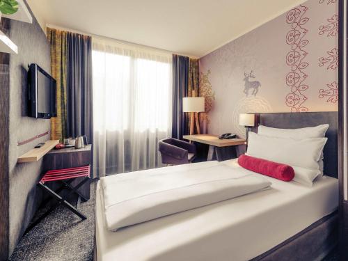 a bedroom with a large white bed and a desk at Mercure München City Center in Munich