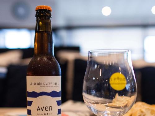 a bottle of beer sitting next to a glass at Mercure Lorient Centre in Lorient