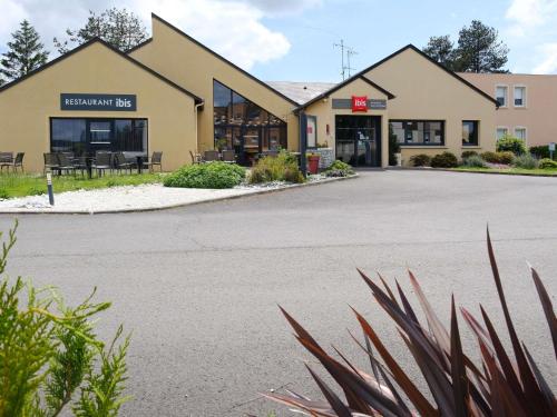 a building with a parking lot in front of it at Ibis Avranches Baie du Mont-Saint-Michel in Saint-Quentin-sur-le-Homme