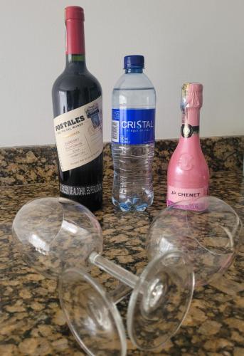 three bottles of wine and glasses on a counter at Aparta Suite Hotel Rioverde Aeropuerto JMC in Rionegro