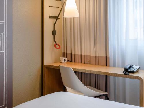 a room with a desk with a chair and a phone at ibis Nürnberg City am Plärrer in Nürnberg