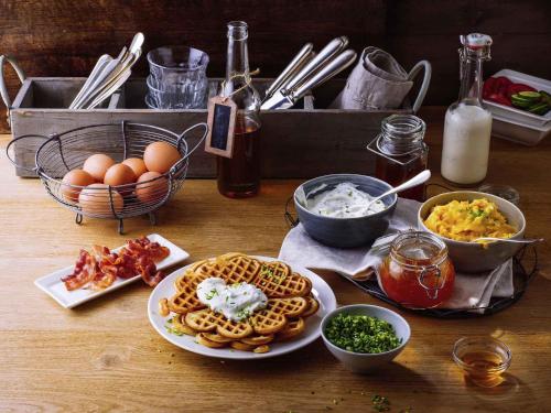 a table topped with waffles and eggs and other food at ibis Nürnberg City am Plärrer in Nürnberg