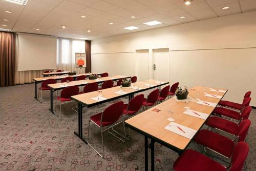 a conference room with long tables and red chairs at ibis Nürnberg City am Plärrer in Nürnberg