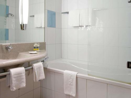 a white bathroom with a tub and a sink at Novotel Zürich Airport Messe - newly renovated in Glattbrugg