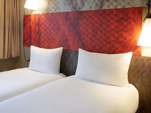 a bedroom with two white beds and a red headboard at ibis Paris Canal Saint Martin in Paris
