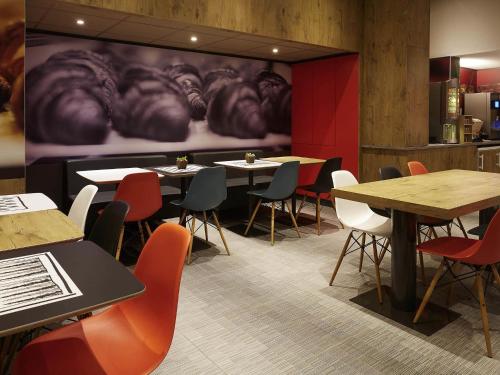 a restaurant with tables and chairs and a large painting of animals at ibis Paris Canal Saint Martin in Paris