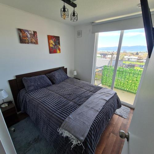 ein Schlafzimmer mit einem Bett und einem großen Fenster in der Unterkunft Departamento 3 dormitorios en villarica in Villarrica