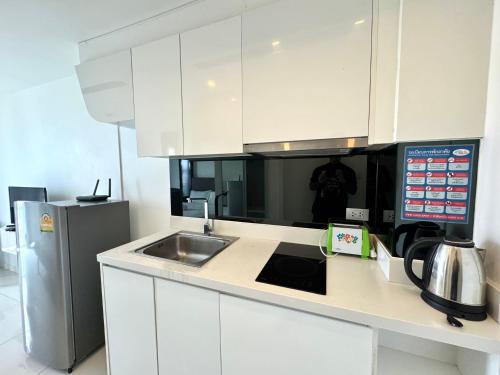 a kitchen with white cabinets and a sink and a refrigerator at City Center Residence KR in Pattaya Central