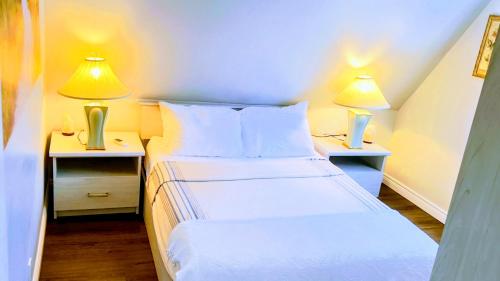 a small bedroom with two beds and two lamps at Granary Guest House in Goderich