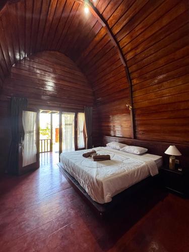 a bedroom with a large bed with a wooden ceiling at Rinjani Koceng Bungalows in Tetebatu
