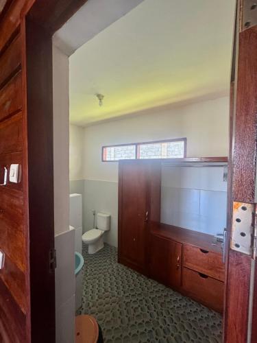 a bathroom with a toilet and a wooden door at Rinjani Koceng Bungalows in Tetebatu